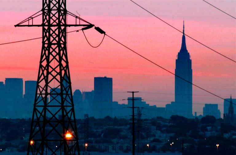 FILE - In a Friday, Aug. 15, 2003 file photo, the Empire State Building towers over the skyline of a blackout-darkened New York City just before dawn.  Power lines from Jersey City, N.J., are in foreground. Ten years after a blackout cascading from Ohio affected 50 million people, utilities and analysts say changes made in the aftermath make a similar outage unlikely today, though shifts in where and how power is generated raise new reliability concerns for the U.S. electric grid system. (AP Photo/File, George Widman, File)