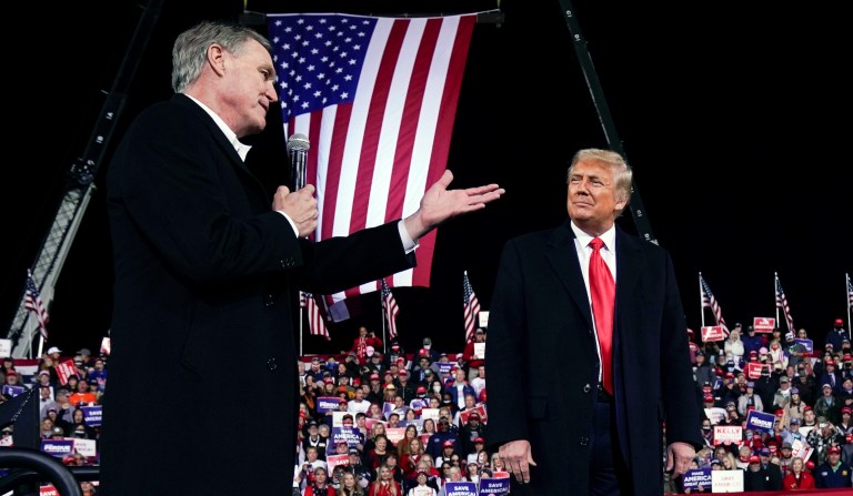 Former Sen. David Perdue of Georgia speaks as President Donald Trump looks on at a campaign rally at Valdosta Regional Airport.