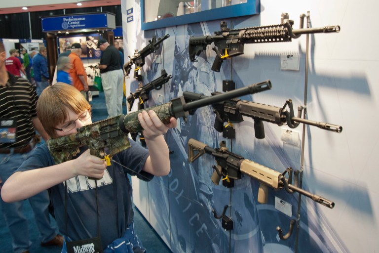 A young man sizes-up an assault style rifle during the National Rifle Association's annual convention Friday, May 3, 2013 in Houston.