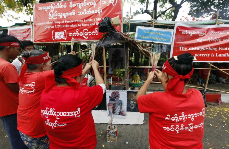 In this Monday, April 28, 2014 photo, land grab victims burn incense sticks and pray in front of a makeshift altar for the âDemon of Earthâ at their protest camp in Yangon, Myanmar. Families from Michaung Kan in eastern Yangon have eagerly tested newfound freedoms by protesting and sending petitions to the president and parliament, to no avail. Now some are turning to old ways: Curses and black magic. Coffins marked with the names of those who seized property have been set ablaze. (AP Photo/Khin Maung Win)