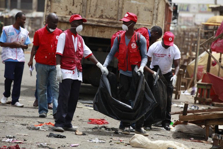 Red Cross personnel search for body parts at the site of one of Tuesday's car bomb in Jos, Nigeria, Wednesday, May 21, 2014. Two car bombs exploded at a bustling bus terminal and market in Nigeria's central city of Jos on Tuesday, killing over 100 people, wounding dozens and leaving bloodied bodies amid the flaming debris. There was no immediate claim of responsibility for the twin car bombs. But they bore the hallmarks of Boko Haram, the Islamic extremist group that abducted nearly 300 schoolgirls last month and has repeatedly targeted bus stations and other locations where large numbers of people gather in its campaign to impose Islamic law on Nigeria. The second blast came half an hour after the first, killing some of the rescue workers who had rushed to the scene, which was obscured by billows of black smoke. (AP Photo/Sunday Alamba)