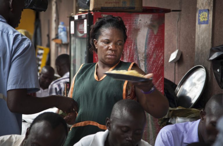 In this photo taken Friday, May 30, 2014, 34-year-old single mother Madinah Nalukenge serves dishes to customers at her food stall, frequented by transport operators, that she owns on the edge of a bus terminal in the capital Kampala, Uganda. About 63 percent of women in the non-agricultural labor force are self-employed in the informal sector in Africa, more than twice the worldwide rate according to World Bank data, which also shows that necessity, not opportunity, is the main driving force behind female entrepreneurship in poor countries. (AP Photo/Rebecca Vassie)