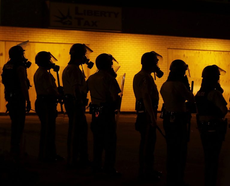 Police wait to advance after tear gas was used to disperse a crowd Sunday during a protest for Michael Brown. (AP/Charlie Riedel)