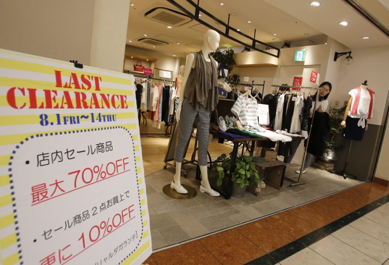 A shopper examines clothes at a store in Tokyo, Wednesday, Aug. 13, 2014. The Japanese economy shrank at an annual pace of 6.8 percent in the second quarter after spending got slammed by a sales tax hike that kicked in from April, government figures showed Wednesday. (AP Photo/Shizuo Kambayashi)