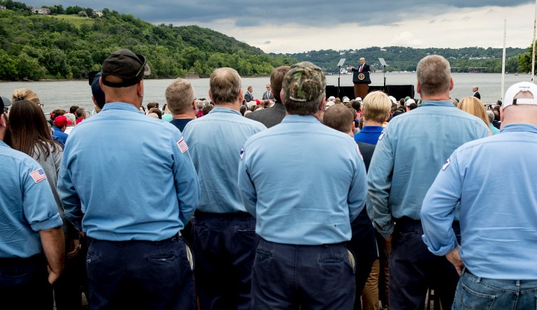 A coal barge is visible behind President Donald Trump as he speaks about infrastructure at Rivertowne Marina in Cincinnati, Ohio, Wednesday, June 7, 2017. (AP Photo/Andrew Harnik)