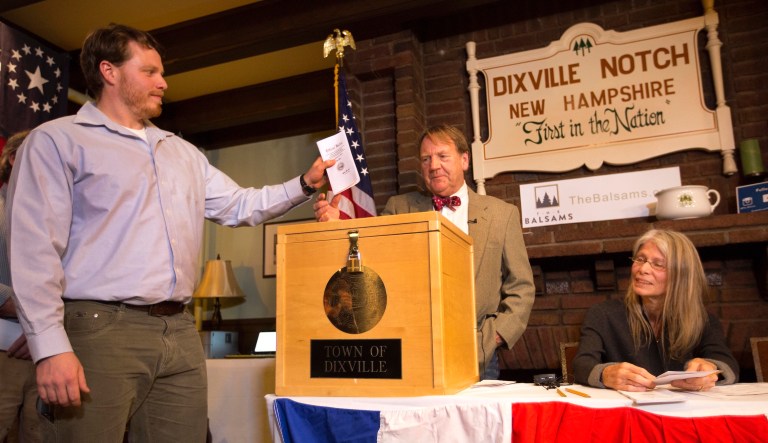 Dixville Notch's first voter Clay Smith drops his ballot into the box as moderator Tom Tillotson watches Tuesday, Nov. 8, 2016, in Dixville Notch, N.H.