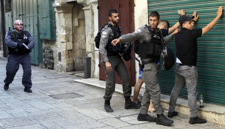 Israeli border police officers body-search Palestinians in Jerusalem's Old City. Three Palestinian assailants opened fire on Israeli police from inside a major Jerusalem holy site Friday, killing two officers before being shot dead, police said. (AP Photo/Mahmoud Illean)