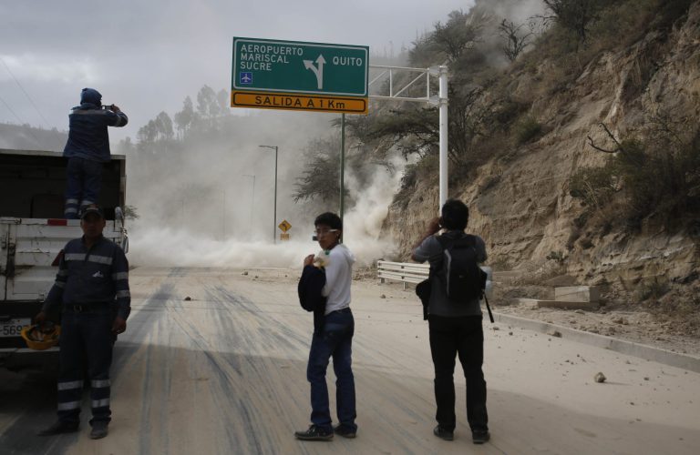 People watch as earth and dust spill on the Pan-American highway as result of an earthquake, at Oyacoto, north of Quito, Ecuador, Tuesday Aug. 12, 2014. A magnitude-5.1 earthquake shook Ecuador's capital and surrounding areas Tuesday, causing tall buildings to sway and sending some people rushing into the streets. (AP Photo/Dolores Ochoa)