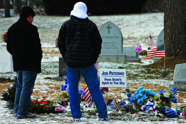 Penn State students Dan Hamm, left, a freshman from Williamsport, Pa., and Nick Bucci, a freshman from Dayton, Md., visit the grave of former Penn State head football coach Joe Paterno in State College, Pa. Supporters of Paterno are marking the 1-year anniversary of his death with a candlelight vigil Tuesday night. (AP Photo/Gene J. Puskar)