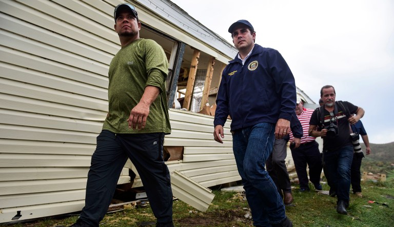 Mayor William Ivan Solis and Puerto Rico Gov. Ricardo Rossello, center, walk past a damaged home. (AP Photo/Carlos Giusti)