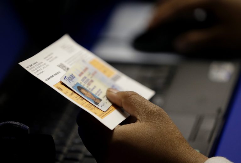 FILE - In this Feb. 26, 2014 file photo, an election official checks a voter's photo identification at an early voting polling site in Austin, Texas. A majority of the nation's highest court on Saturday Oct. 18, 2014 rejected an emergency request from the Justice Department and civil rights groups to prohibit the state from requiring voters to produce certain forms of photo identification in order to cast ballots. (AP Photo/Eric Gay, File)