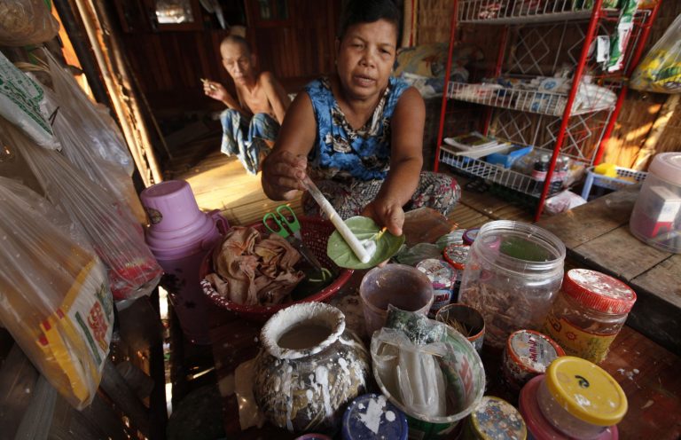 In this May 1, 2014 photo, Tin Hsan, a woman whoâs family was forced move to make way for Thilawa Special Economic Zone, applies lime in to a betel leaf, sitting in her new home, in suburbs of Yangon, Myanmar. âMy husband is a farmer and he only knows how to work in the field. Since he has no work to do, he became depressed and is now drinking day and night,â said Tin Hsan, sitting in their rickety, one-room hut that fills a barren roadside lot. âSince we moved here and live in this small place with no space to grow anything, we are living hand to mouth and we are all miserable.â (AP Photo/Khin Maung Win)