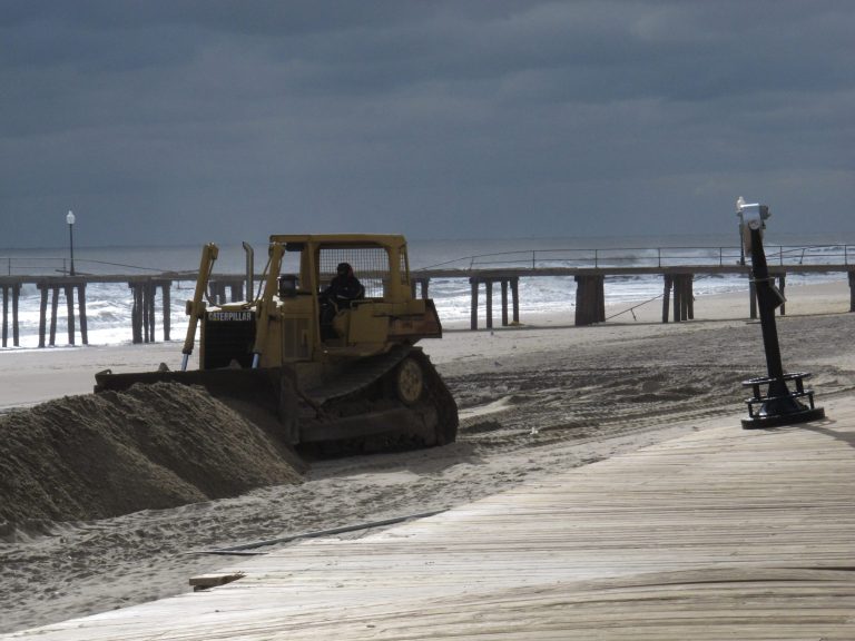 This Nov. 15, 2012 photo shows a bulldozer moving sand on the Ocean Grove N.J. beachfront in front of a boardwalk damaged by Superstorm Sandy, two weeks after the storm hit. A funding dispute with the federal government has delayed the rebuilding of Ocean Grove's boardwalk, but the project is now under way and should be completed by the end of June 2014. (AP Photo/Wayne Parry)