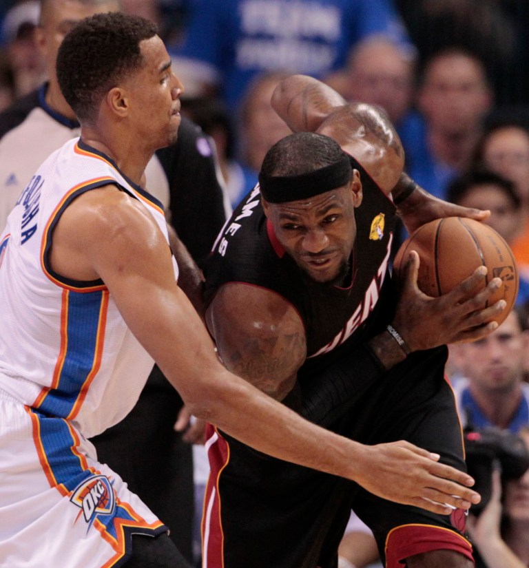   Miami Heat small forward LeBron James is guarded by Oklahoma City Thunder shooting guard Thabo Sefolosha (2) of Switzerland during the first half at Game 2 of the NBA finals basketball series, Thursday, June 14, 2012, in Oklahoma City. (AP Photo/Jeff Roberson)  