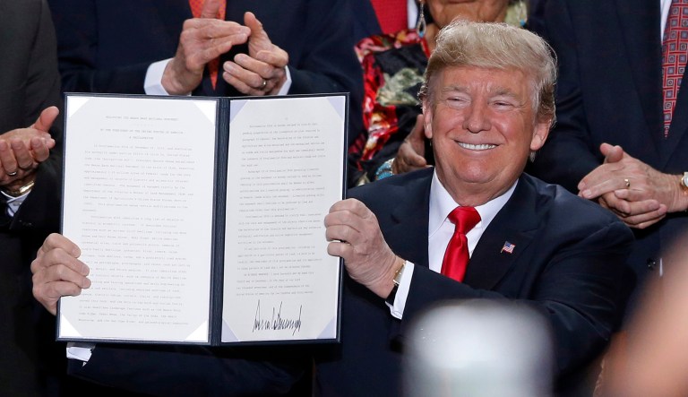 President Trump holds up a signed proclamation to shrink the size of Bears Ears and Grand Staircase-Escalante national monuments. The proclamation cuts Bears Ears by more than 1.1 million acres, or 85 percent, and creates two smaller monuments instead. (AP Photo/Rick Bowmer)