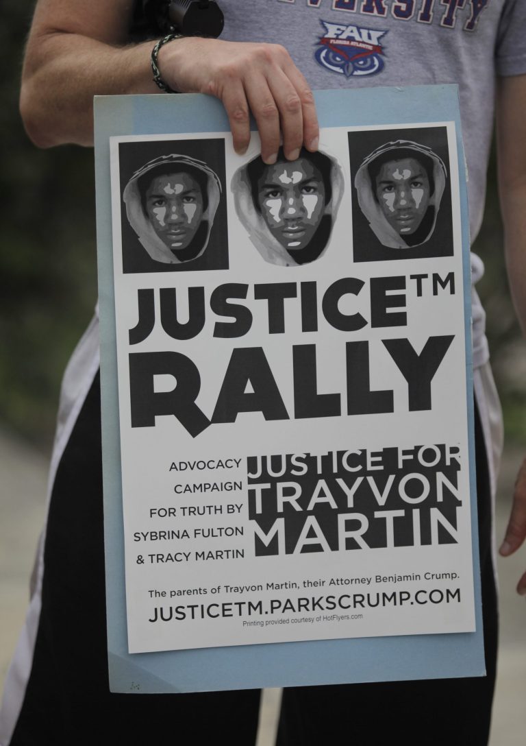 A demonstrators holds up a sign as he attends a vigil for Trayvon Martin at the Torch of Friendship monument on Sunday, in Miami, Fla. (AP/Javier Galeano)
