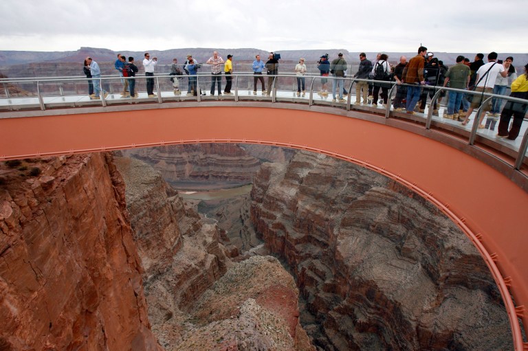 FILE - In this March 20, 2007 file photo, people walk on the Grand Canyon Skywalk on the Hualapai Indian Reservation in Grand Canyon National Park in Arizona. A ceremony is planned Tuesday, Aug. 12, 2014 to mark completion of a newly-paved road which leads to the Skywalk. Known as the Diamond Bar Road, the once rugged, nine-mile washboard road cost more than $30 million to finish and came after years of legal battles with a local dude rancher. (AP Photo/Ross D. Franklin, File)