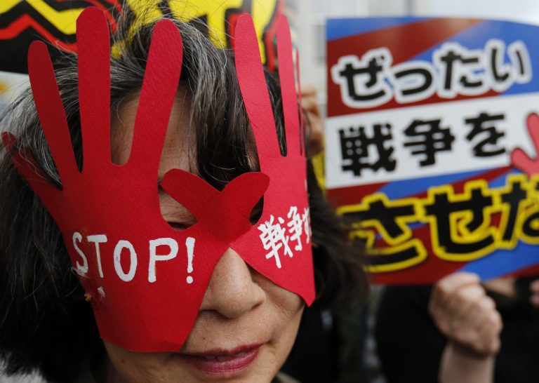 FILE - In this Thursday, June 26, 2014, a protester wears a hand-shaped mask reading: 