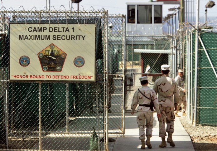FILE - In this June 27, 2006 file photo, reviewed by a U.S. Department of Defense official, U.S. military guards walk within Camp Delta military-run prison, at the Guantanamo Bay U.S. Naval Base, Cuba. President Barack Obama is pushing to overcome obstacles to closing the Guantanamo Bay prison, an elusive goal which has frustrated him since he took office. That is setting the White House on a collision course with Congress in its bid to loosen restrictions for moving out detainees.  (AP Photo/Brennan Linsley, File)