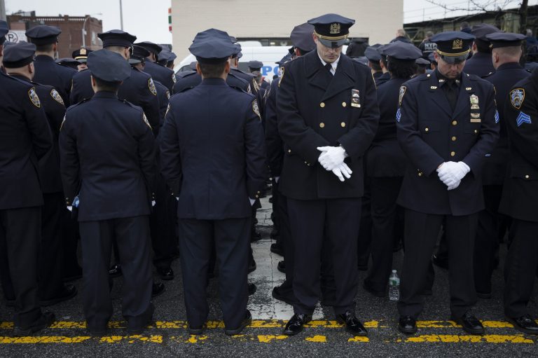 Some police officers, left, turn their backs in a sign of disrespect as Mayor Bill de Blasio speaks as others, at right front line, stand at attention, during the funeral of New York Police Department Officer Wenjian Liu at Aievoli Funeral Home, Sunday, Jan. 4, 2015, in the Brooklyn borough of New York. Liu and his partner, officer Rafael Ramos, were killed Dec. 20 as they sat in their patrol car on a Brooklyn street. The shooter, Ismaaiyl Brinsley, later killed himself. (AP Photo/John Minchillo)