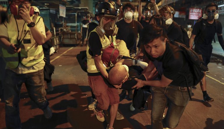 Medical staff and protesters carry an injured man as they face off with policemen near the Shum Shui Po police station in Hong Kong, Wednesday, Aug. 14, 2019. 