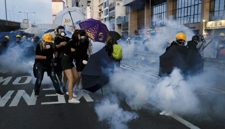 Protesters react from tear gas as they face off with riot policemen on a streets in Hong Kong.