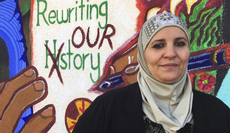 Samia Assedm, activist, stands in front of a mural at the Albuquerque Center for Peace and Justice coalition in Albuquerque, N.M. 