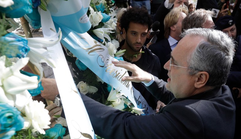 Lazio soccer team president Claudio Lotito, accompanied by Lazio player Felipe Anderson, center, places a wreath outside Rome's Synagogue, Tuesday, Oct. 24, 2017. Lazio fans have a long history of racism and anti-Semitism and the Roman club's supporters established another low over the weekend when they littered the Stadio Olimpico with superimposed images of Anne Frank, the young diarist who died in the Holocaust, wearing a jersey of city rival Roma. (AP Photo/Gregorio Borgia)