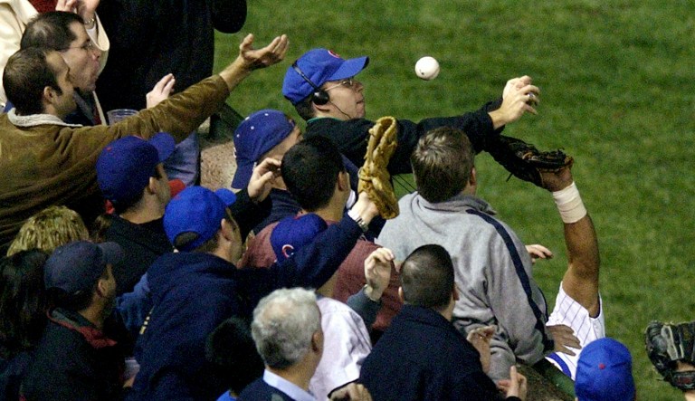 FILE - In this Oct 14, 2003, file photo, Steve Bartman, top center, catches a ball as Chicago Cubs left fielder Moises Alou's arm is seen reaching into the stands, at right, against the Florida Marlins in the eighth inning during Game 6 of the National League championship series Tuesday, Oct. 14, 2003, at Wrigley Field in Chicago. The Cubs announced Monday, July 31, 2017, they were giving a 2016 World Series championship ring to Bartman, the fan remembered for deflecting a foul ball that appeared destined to land in left fielder Moises Alou's glove with Chicago five outs from the World Series in 2003. (AP Photo/Morry Gash, File)