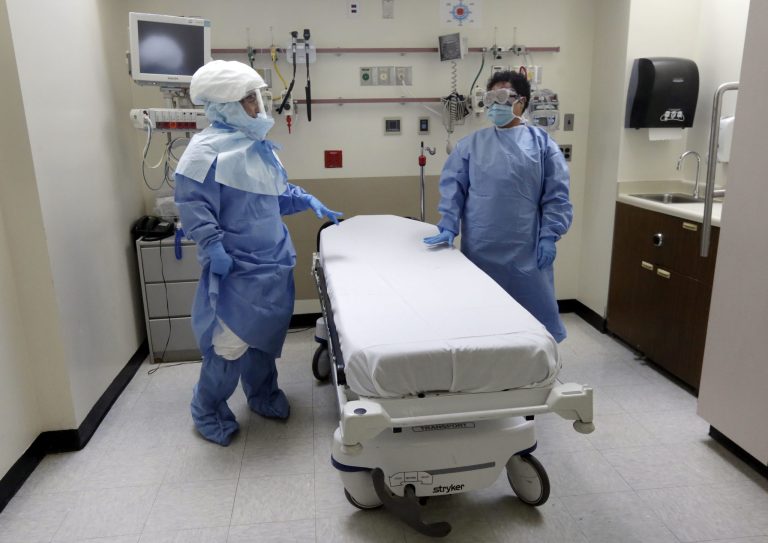 Â Bellevue Hospital nurse Belkys Fortune, left, and Teressa Celia, Associate Director of Infection Prevention and Control, wear protective suits in an isolation room in the Emergency section of the hospital during a demonstration of procedures for possible Ebola patients in New York. Ebola came to New York via Dr. Craig Spencer, who had been treating patients in Guinea. Spencer alerted his aid agency that he had developed a fever, and was transported to Bellevue by specially trained emergency workers cloaked in protective gear. (AP Photo/Richard Drew, File)