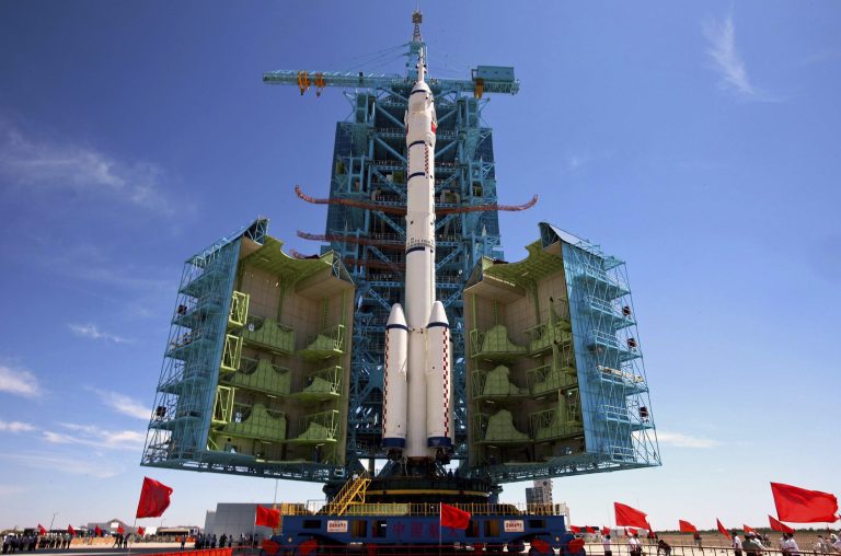   People watch the Long March-2F rocket carrying the Shenzhou-9 spacecraft which moves to the launch pad at the Jiuquan launch center in Jiuquan, China's northwest Gansu province, Saturday, June 9, 2012. China will launch three astronauts this month to dock with an orbiting experimental module, and the crew might include its first female space traveler, a government news agency said Saturday. (AP Photo) CHINA OUT  