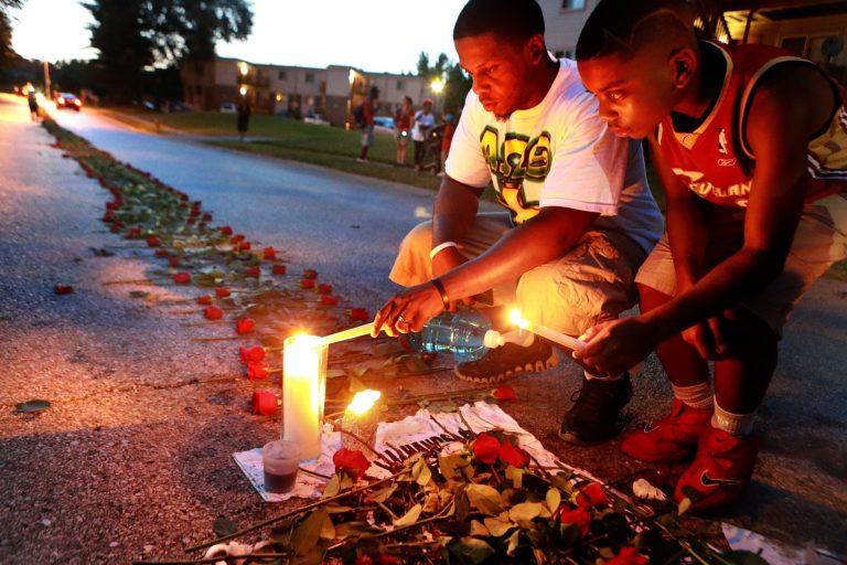 Theo Murphy, left, of Florissant, Mo., and his brother Jordan Marshall, 11, light candles at a memorial on Canfield Drive in Ferguson, Mo., where where unarmed Michael Brown was fatally shot by Ferguson Police Officer Darren Wilson. (AP Photo/St. Louis Post-Dispatch, Christian Gooden)