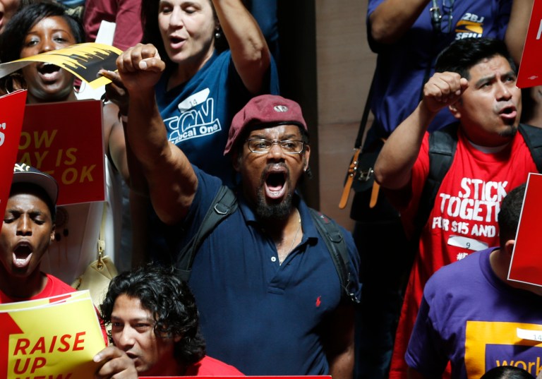 People rally for an increase in the minimum wage on the Great Western Staircase at the Capitol on Tuesday, June 17, 2014, in Albany, N.Y. Several hundred fast-food workers and other low-wage employees from around New York gathered to pressure lawmakers to raise the minimum wage from $8 to $10.10 an hour and let local cities raise it even higher. (AP Photo/Mike Groll)
