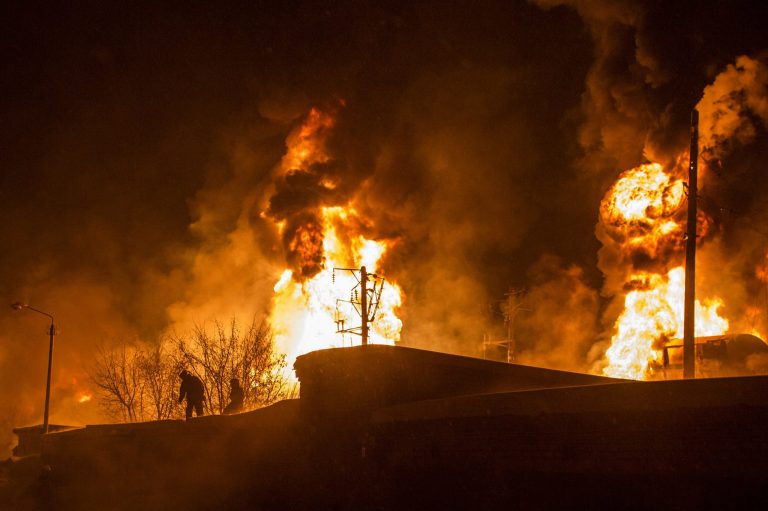 In this photo provided by the Ministry of Emergency Situations Kirov Branch press service, men are silhouetted against burning tankers early Wednesday, Feb. 5, 2014, near Posdino in Kirov region of Russia, some 800 km ( about 500 miles) northeast of Moscow. 32 tankers were derailed and 12 of them burned. No casualties were reported. (AP Photo/ Ministry of Emergency Situations, Kirov Branch Press Service)