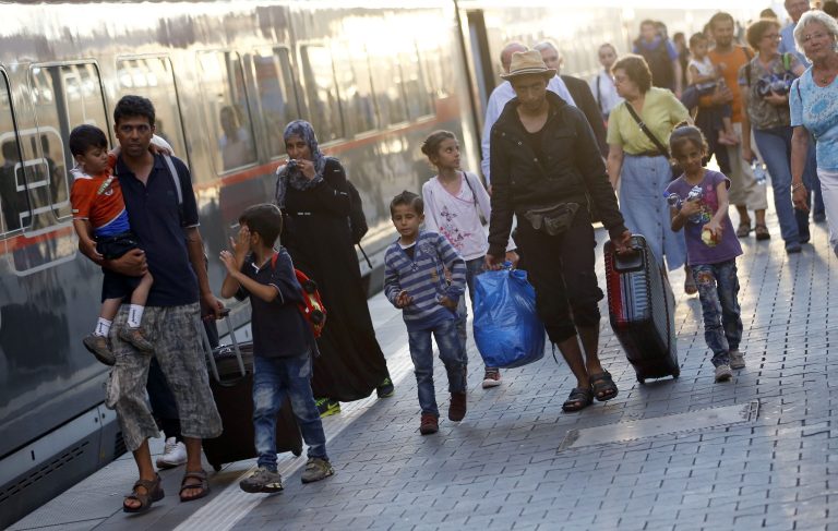 Young and old migrants, along with local people, disembark from a train coming from Austria at the main station in Munich, Germany, Monday, Aug. 31, 2015. (AP Photo/Matthias Schrader)