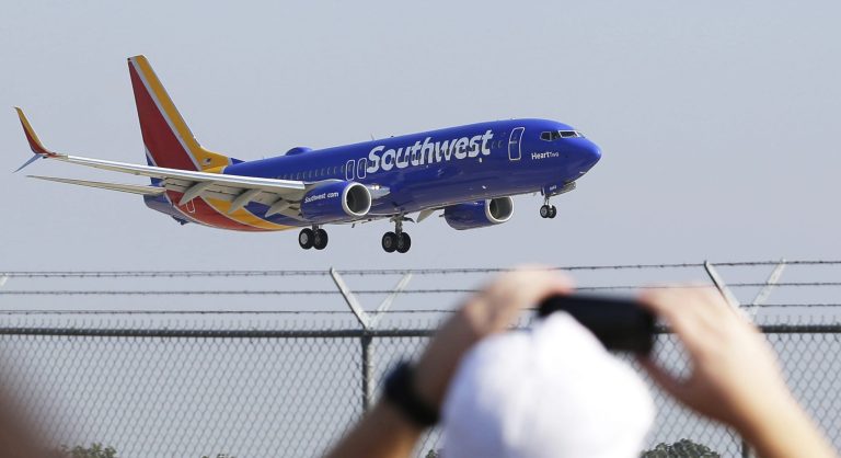 FILE - In this Sept. 8, 2014 file photo, a Southwest Airlines plane with a new paint job flies over Love Field in Dallas. On Monday, Oct. 13, 2014, Southwest will launch its first long-distance flights from its home base at Dallas Love Field to seven cities across the country, with eight more destinations next month. Such flights were prohibited until now by a longtime law that protected Dallas-Fort Worth International Airport by limiting flights from Love Field to a few nearby states.