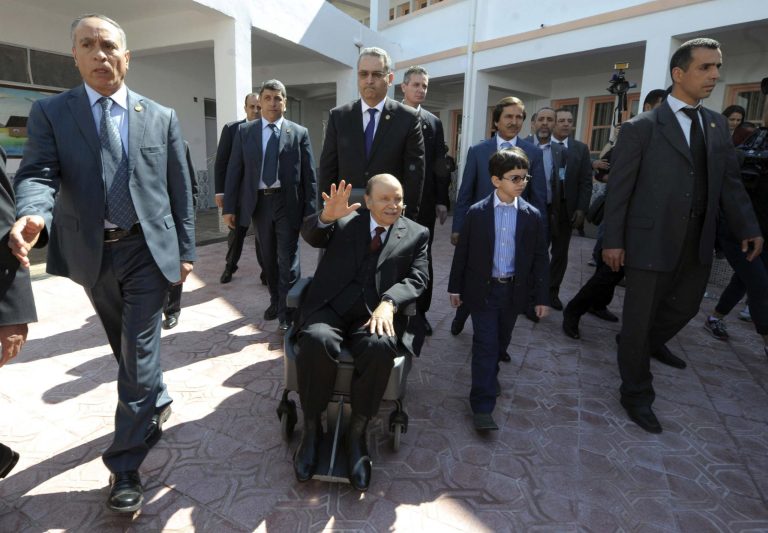 FILE - This Thursday, April 17, 2014, file photo shows President Abdelaziz Bouteflika, centre, in a wheelchair, waving as he leaves after voting in the presidential elections in Algiers. The absence of ailing Algerian President Abdelaziz Bouteflika in the aftermath of the kidnap and murder of a French hiker has re-ignited the debate over his fitness to rule this oil-rich North African nation that is a key ally in the fight against terror. Despite suffering from a stroke last year and being largely absent from the election campaign, Bouteflika still won a fourth term in April but has been barely seen since. . (AP Photo/Sidali Djarboub, File)