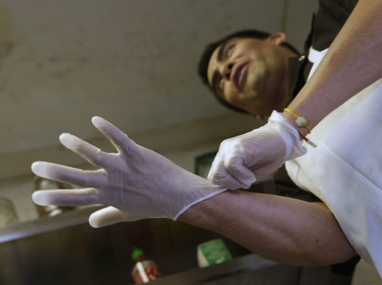 Luis Escamilla puts on gloves before cutting prosciutto at the Hock Farm Restaurant  in Sacramento, Calif.  at the Hock Farm restaurant in Sacramento, Calif. Under a bill signed last year by Gov. Jerry Brown, chefs and bartenders in California must keep bare hands off food going straight to the plate or the drink glass, and must use gloves or kitchen utensils such as tongs.  California, where the law took effect Jan. 1 and will begin enforcement starting in July, will join 41 other states banning bare-hand contact with ready-to-eat food.  In February,after receiving a petition from bartenders calling for an exemption for the 