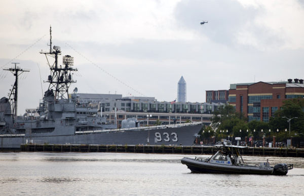 A police boat and helicopter patrol near the scene of a shooting at the Washington Navy Yard on Monday, Sept. 16, 2013, in Washington. At least one gunman opened fire inside a building at the Washington Navy Yard, and officials said six people were killed and as many as 10 were wounded, including a law enforcement officer. (AP Photo/ Evan Vucci)