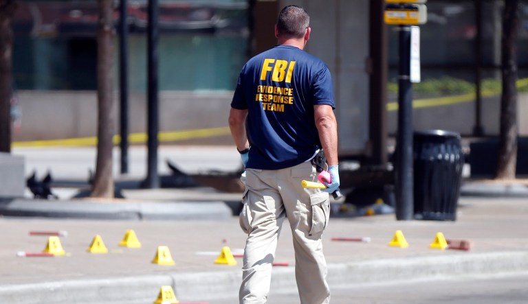 An FBI evidence response team member walks near evidence markers at the scene where one or more gunmen opened fire on Dallas police officers.