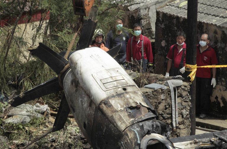 Emergency workers watch an engine lifted from the TransAsia Airways Flight GE222 crash site on the outlying Taiwan island of Penghu, Friday, July 25, 2014. Investigators on Friday were examining wreckage and flight data recorders for clues into a plane crash on the Taiwanese island that killed 48 people. (AP Photo/Wally Santana)