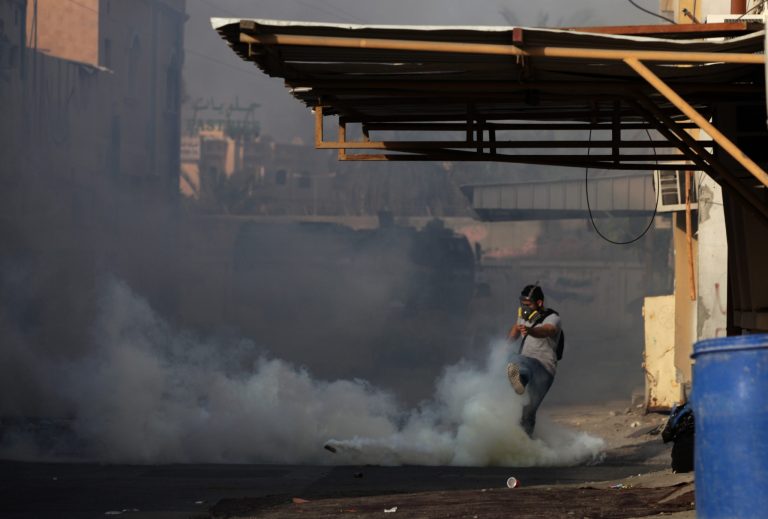 A Bahraini anti-government protester kicks away a tear gas canister fired by riot police during clashes in Abu Saiba, Bahrain, near the capital, Manama, Friday, May 30, 2014. Clashes erupted after authorities banned a plan opposition gathering. (AP Photo/Hasan Jamali)