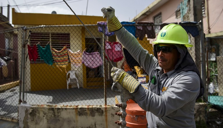In this Thursday, Oct. 19, 2017 photo, Ezequiel Rivera works with the Electric Energy Authority to restore distribution lines damaged by Hurricane Maria in the Cantera community of San Juan, Puerto Rico. (AP Photo/Carlos Giusti)