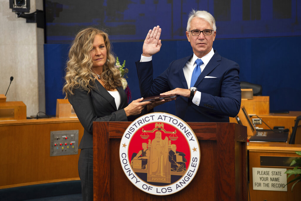 In this photo provided by the County of Los Angeles, incoming Los Angeles County District Attorney George Gascon is sworn in as his wife Fabiola Kramsky holds a copy of the Constitution during a mostly-virtual ceremony in downtown Los Angeles on Dec. 7, 2020.