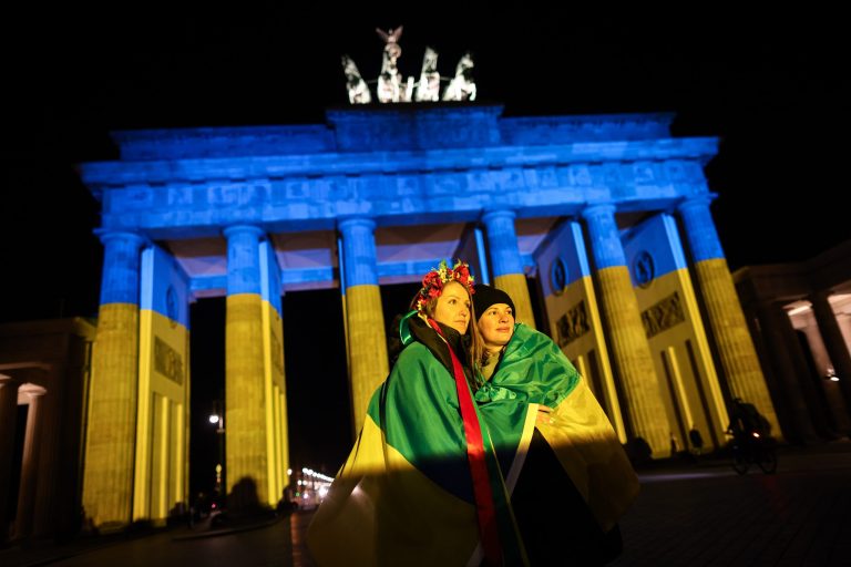 Two women draped in flags pose for a photo in front of the Brandenburg Gate, as it is lit in the blue and yellow colours of the Ukrainian national flag in solidarity with Ukraine and its people on Wednesday in Berlin, Germany.