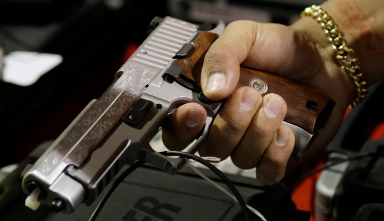 FILE - In this Jan. 9, 2016, file photo, a customer looks at a SIG Sauer hand gun at a gun show held by Florida Gun Shows in Miami.