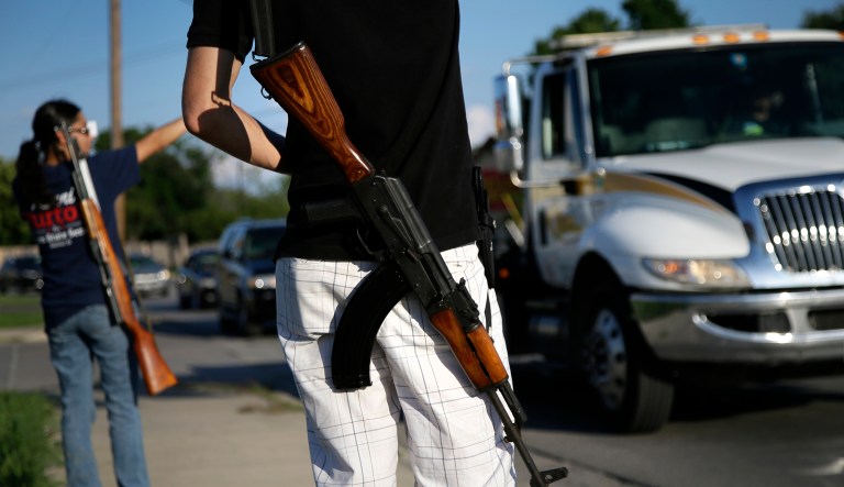 FILE - In this May 29, 2014, file photo, Kory Watkins, front, coordinator for Open Carry Tarrant County, carries his Romanian AK 47 over his shoulder as he and his wife Janie, rear, along with others, gather for a demonstration in Haltom City, Texas. Companies, customers and others critical of Texas gun rights advocates who have brought military-style assault rifles into businesses as part of demonstrations supporting "open carry" gun rights now have a surprising ally: the National Rifle Association. The NRA has long been a zealous advocate for gun owners' rights. But the group's lobbying arm, the Institute for Legislative Action, has called the demonstrations counterproductive to promoting gun rights, scary and "downright weird." 