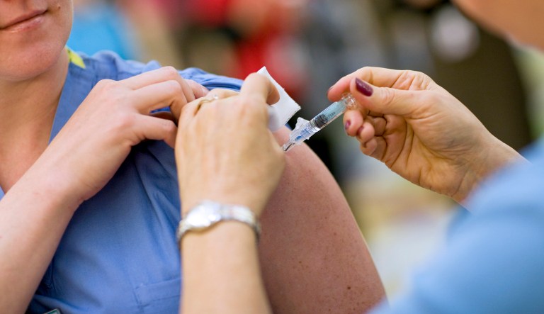 Katie Miller, RN, gets the regular seasonal vaccine while she and other employees wait in line to receive the seasonal and the H1N1 flu vaccine inside The Children's Hospital in Aurora, Colorado, U.S., on Tuesday, October 13, 2009.