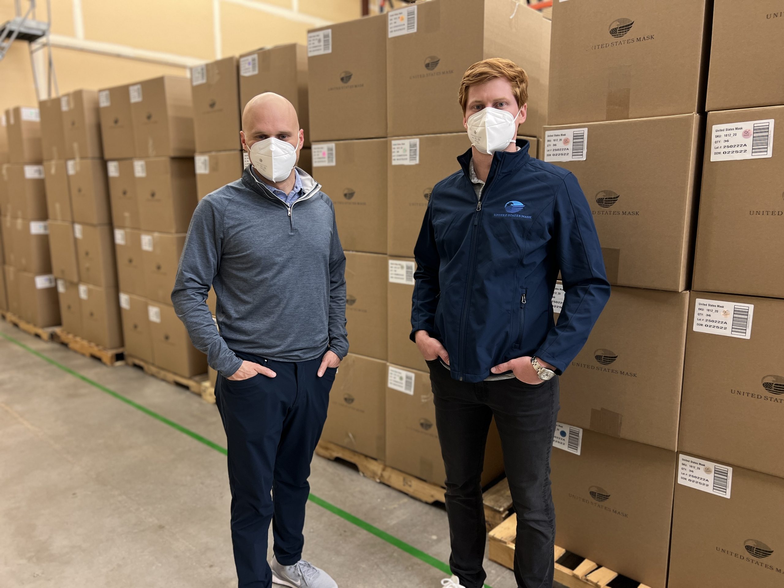 John Bielamowicz (left) and David Baillargeon (right), the co-founders of United States Mask, stand in front of boxes filled with N95 at a warehouse. The duo founded the company in 2020 during the onset of the pandemic.