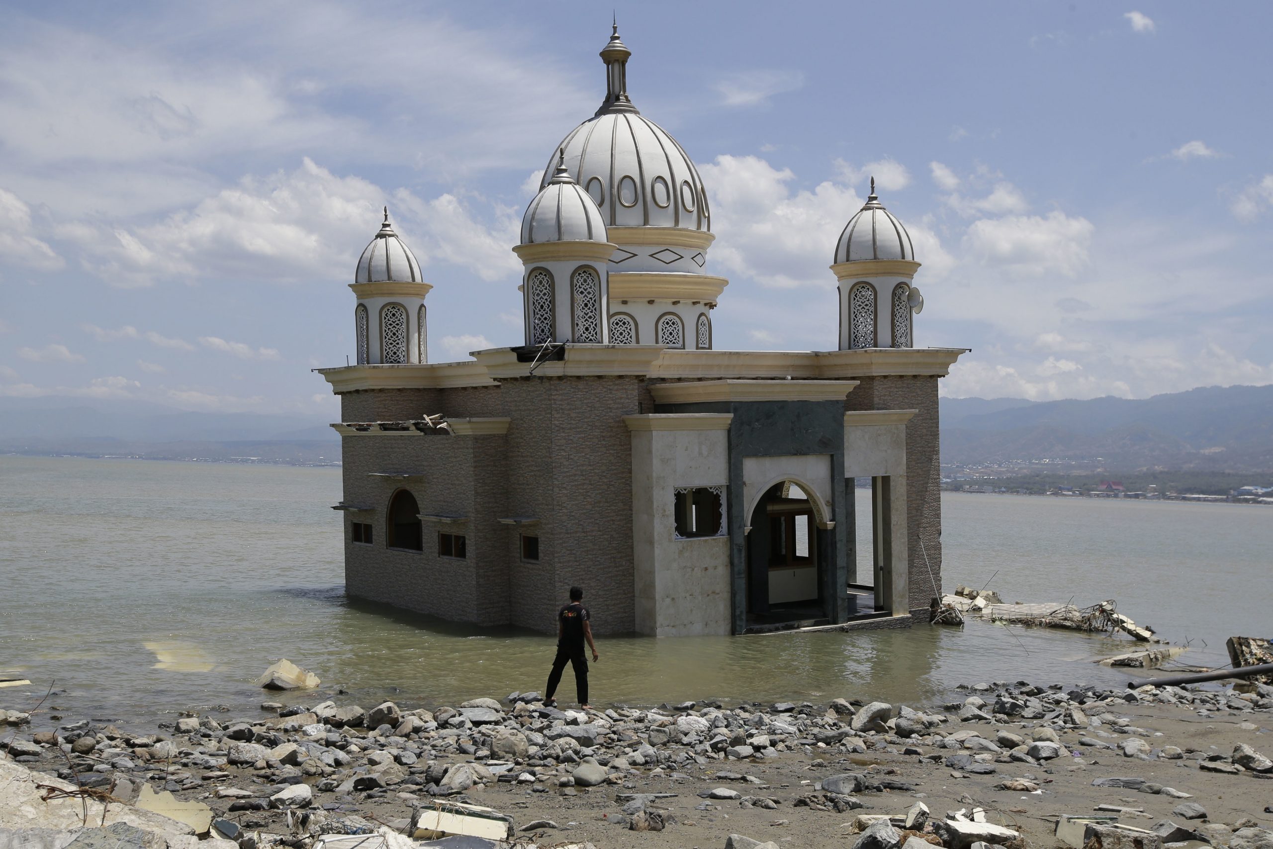 A man looks at a mosque that is isolated by water after its bridge was broken due to the massive earthquake and tsunami in Palu, Central Sulawesi, Indonesia, on Friday.